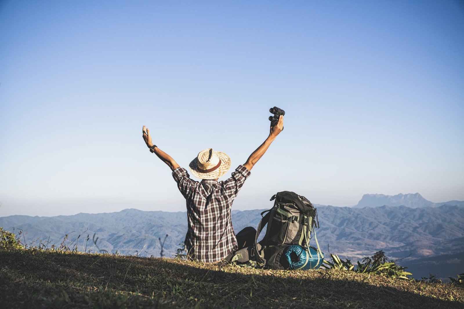 Tourist from mountain top. sun rays. man wear big backpack agai